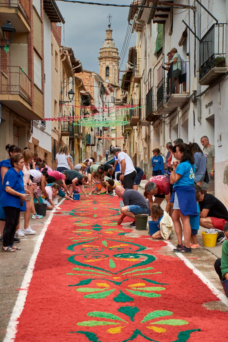 People creating a large floral pattern on a town street.