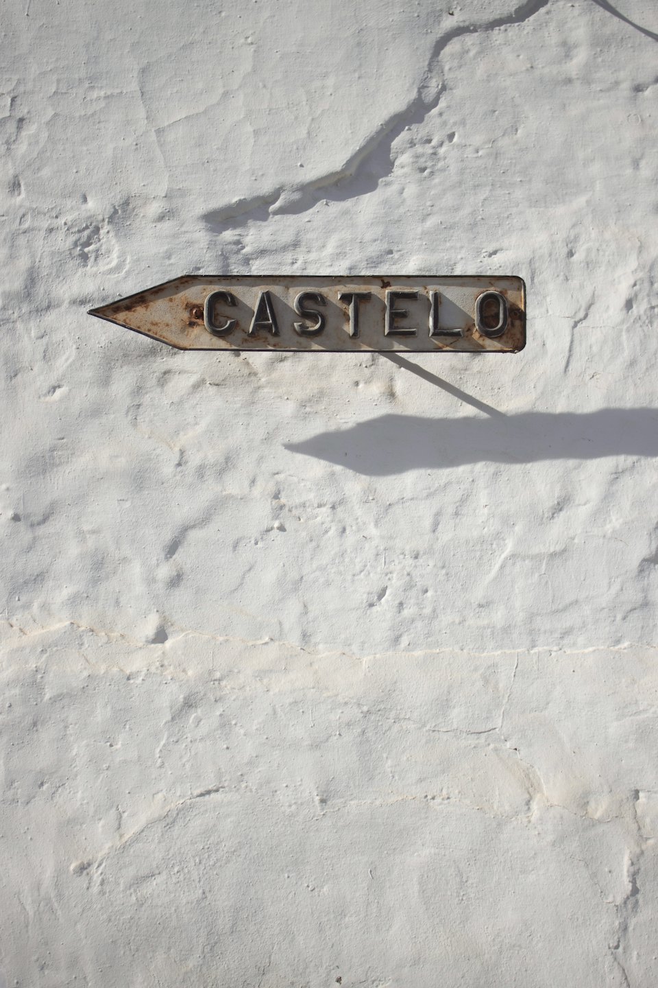 A rusty metal sign labeled Castelo mounted on a wall.